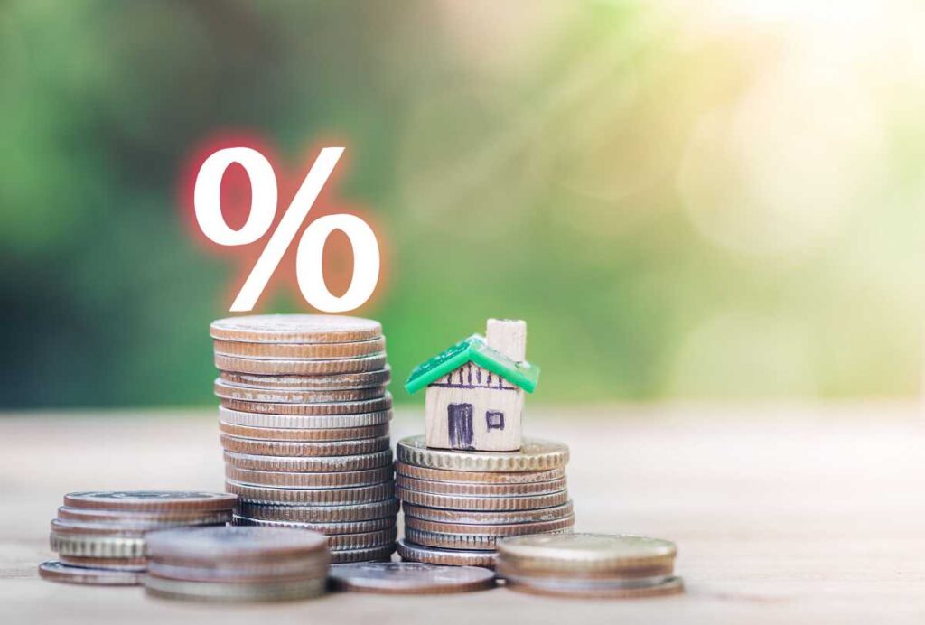 금리(interest rate)의 감소_나무 테이블 위에 집과 동전